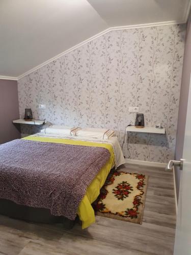a bedroom with a bed and a wall with wallpaper at O pallar in Bardaos