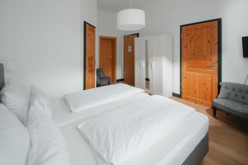 a bedroom with a large white bed and a chair at Logierhaus am Denkmal in Norderney