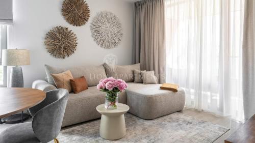 uma sala de estar com um sofá e uma mesa com flores em Lion Apartments - SCALA City Center Apartments&Parking IK em Gdansk
