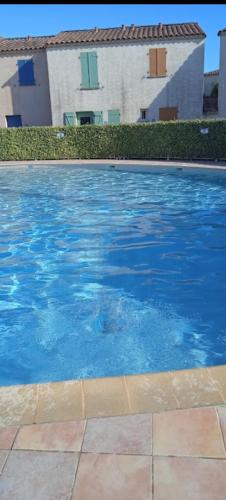 une piscine avec de l'eau bleue devant un immeuble dans l'établissement IRIS, à Aigues-Mortes