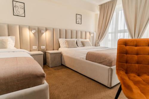 a hotel room with two beds and a chair at Pensiunea Elisei in Timişoara