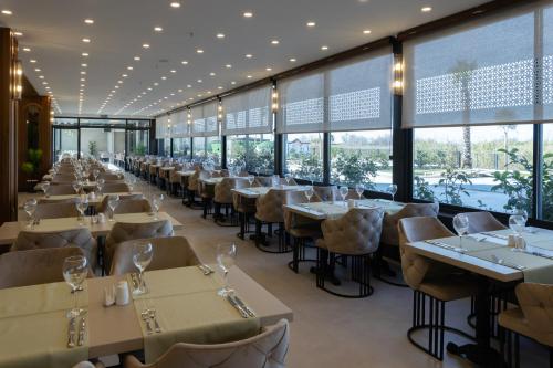 a restaurant with tables and chairs and windows at Belenli Resort Hotel in Belek