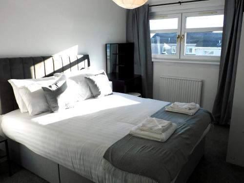 a bedroom with a large bed with two towels on it at New & delightful 3 bed house in East Kilbride in Glasgow