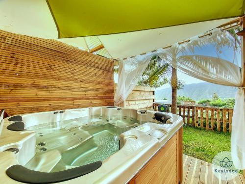 a large bath tub in a room with a wooden wall at Joli Coeur - Bungalow aux Makes - Saint-Louis in Saint-Louis