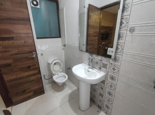 een badkamer met een toilet, een wastafel en een spiegel bij Hotel Pearl Grand Prime in Karnal