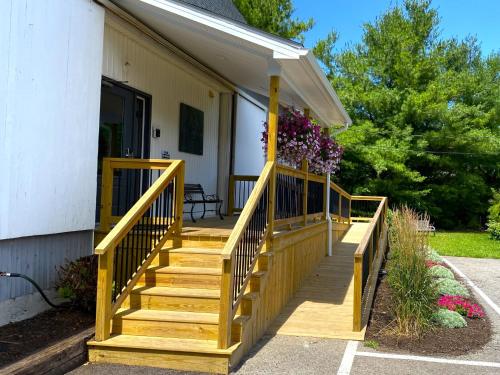 a house with a wooden deck with flowers on it at Lake Ontario Motel & Inn in Newfane