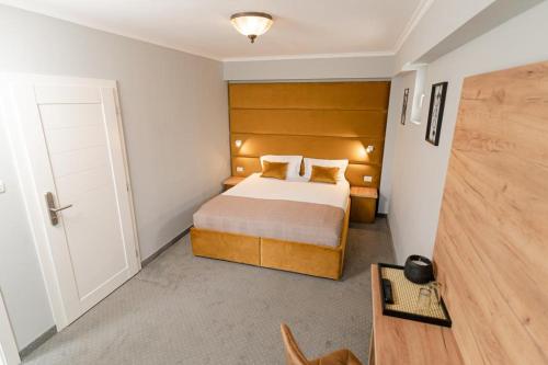 a bedroom with a bed with a wooden headboard at Pensiunea Elisei in Timişoara
