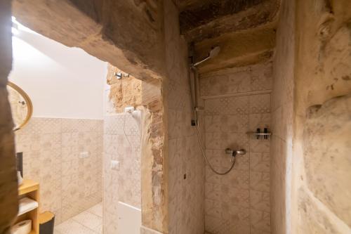 a bathroom with a shower in a stone wall at Fjore di Lecce, camere & caffè in Lecce