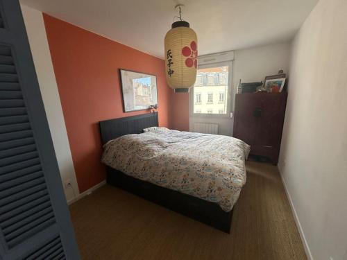 a bedroom with a bed with an orange wall at Appartement familial avec balcon et parking in Lyon