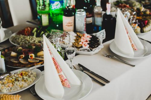 a table with plates of food and glasses of wine at Tulipan Hotel Aquapark in Vyshkove
