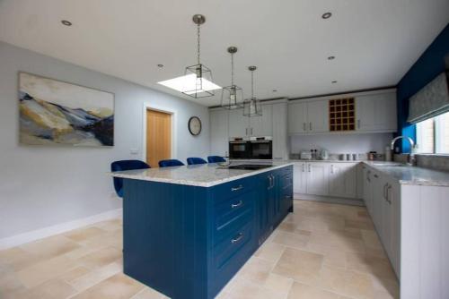 a large kitchen with blue cabinets and a blue island at Beautiful 4 bed semi rural house in Southam