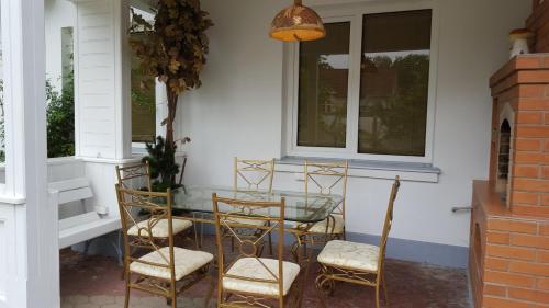 a glass table and four chairs on a porch at Naiza Guesthouse and Apartments in Jūrmala