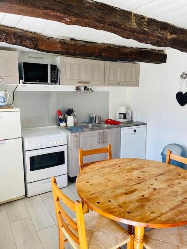 une cuisine avec une table en bois et une table et des chaises dans l'établissement Une Chaumière à Port Manech', à Névez