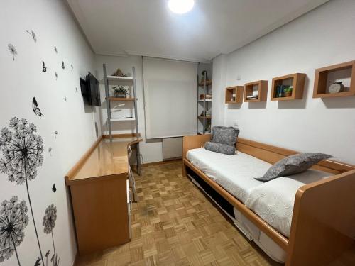 Habitación pequeña con cama y escritorio. en Alojamiento BULEVAR, en Alba de Tormes