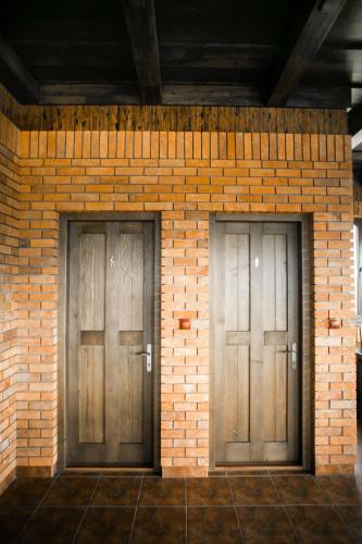 two wooden doors on a brick wall at Tulipan Hotel Aquapark in Vyshkove