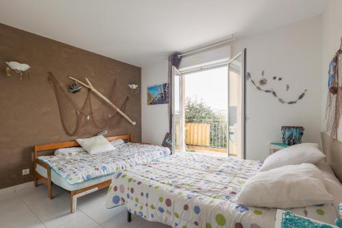 una camera da letto con due letti e una grande finestra di Vue Marine - Appartement proche plage a LʼÎle-Rousse
