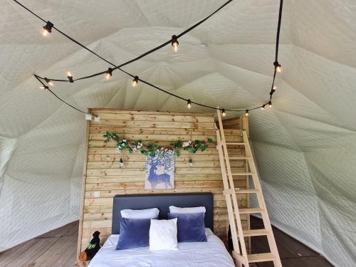 1 dormitorio en una tienda de campaña con cama y escalera en Parkhoeve Glamping, en Ham