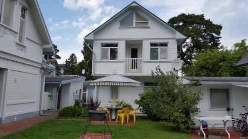 a white house with a table and chairs in the yard at Naiza Guesthouse and Apartments in Jūrmala