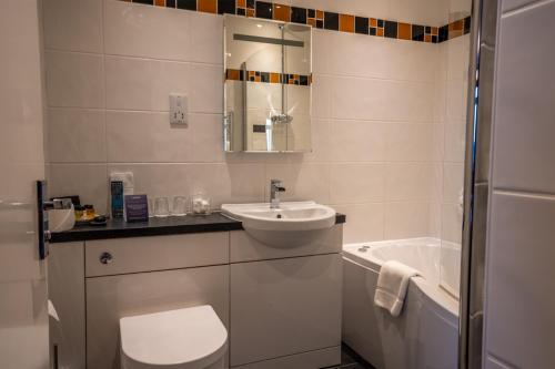a bathroom with a sink and a toilet and a tub at Cairndale Hotel & Spa in Dumfries