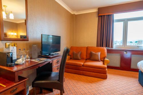 um quarto de hotel com uma secretária com um computador e um sofá em Cairndale Hotel em Dumfries