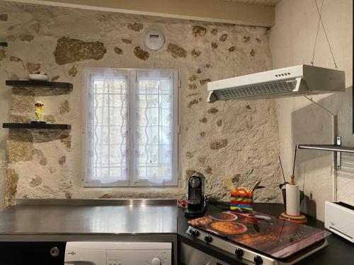 une cuisine avec une cuisinière et une fenêtre. dans l'établissement maison de village atypique, à Saint-Geniès-de-Fontedit