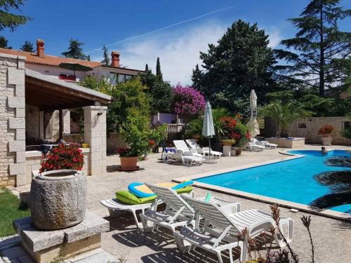 une villa avec une piscine, des chaises et une maison dans l'établissement Ferienwohnung für 4 Personen in Buici, Istrien, à Buici