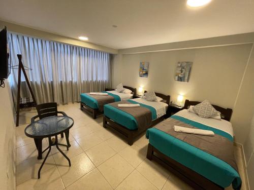 een hotelkamer met 4 bedden en een stoel bij Vianca Hotel in Machu Picchu