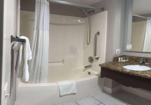 a bathroom with a tub and a sink and a shower at Days Inn by Wyndham Port Charlotte Town Center in Port Charlotte