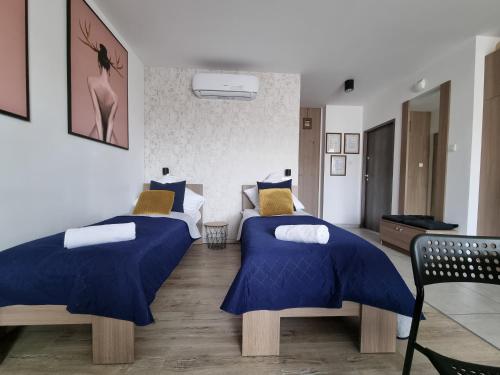 1 Schlafzimmer mit 2 Betten mit blauen und gelben Kissen in der Unterkunft Q Apart AMBER - garaż, Manufaktura klimatyzacja Netflix,FV STUDIO in Łódź