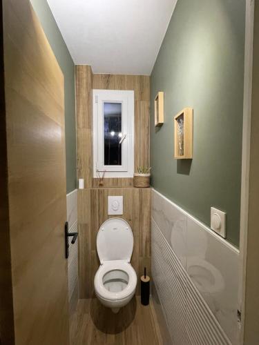 a bathroom with a toilet and a window at Chambre 24h Le Mans in Guécélard