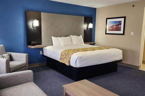 ダベンポートにあるBaymont by Wyndham Davenportの大きなベッドと椅子が備わるホテルルームです。