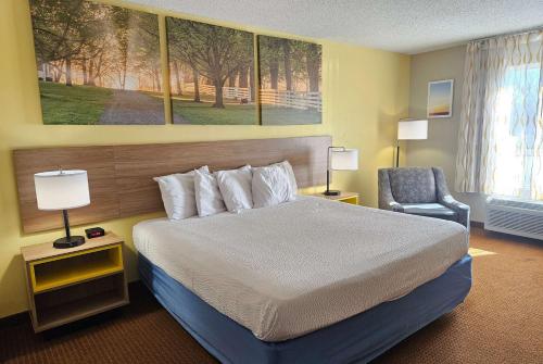 a hotel room with a bed and a chair at Days Inn by Wyndham Greensboro NC in Greensboro