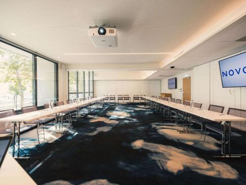 une salle de conférence avec des tables, des chaises et une scène dans l'établissement Novotel Le Havre Centre Gare, au Havre
