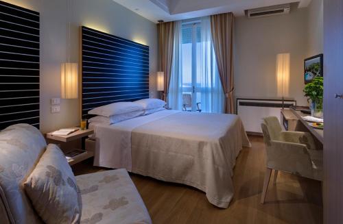 een hotelkamer met een groot bed en een bureau bij Color Alexandra Plaza Family Hotel in Riccione