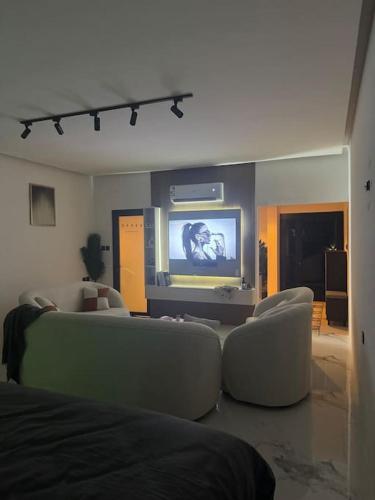 a living room with couches and a flat screen tv at استديو بجاكوزي وكراج دخول ذاتي in Ruqaiqah