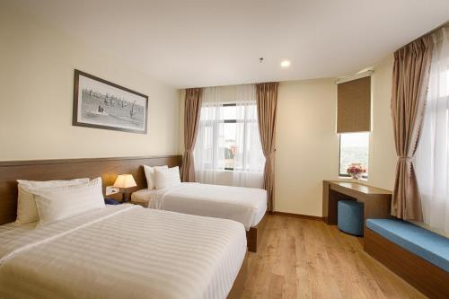 a hotel room with two beds and a couch at Central Hotel & Spa Danang in Da Nang
