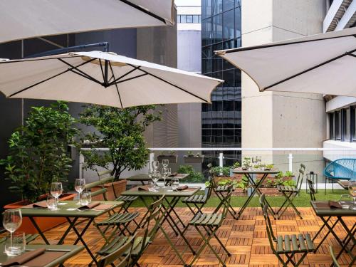 un patio con mesas, sillas y sombrillas en Mercure Milano Agrate Brianza, en Agrate Brianza