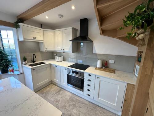 a kitchen with white cabinets and a stove top oven at Peacock cottage in Ewenny