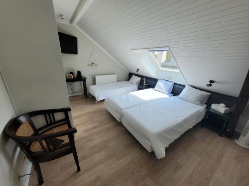 un dormitorio en el ático con 2 camas y una silla en Parkhoeve Vakantiewoning, en Ham