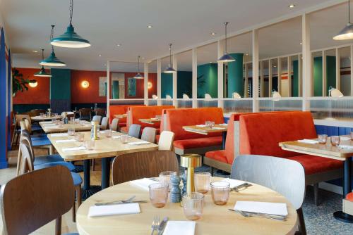 a restaurant with wooden tables and red chairs at Hilton Cobham in Cobham