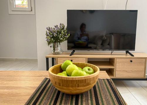 a bowl of green apples in a living room with a television at Nikol's House in Chania