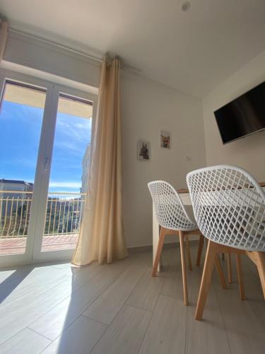ein Esszimmer mit einem Tisch, Stühlen und einem Fenster in der Unterkunft Due Golfi Heart in Massa Lubrense