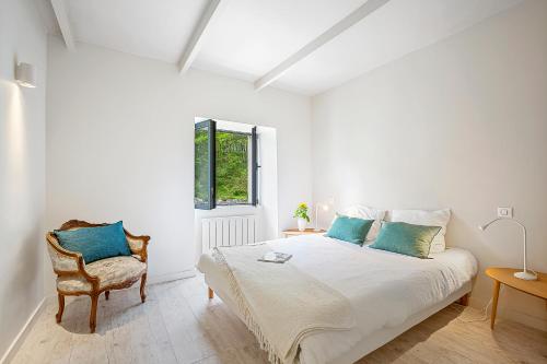 une chambre blanche avec un lit et une chaise dans l'établissement Le Moulin et sa Bergerie, à Saint-Vallier-de-Thiey