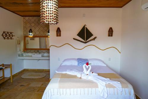 Un dormitorio con una cama con sábanas blancas y una lámpara de araña. en Casa do velejador en Barra Grande