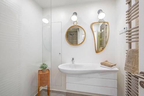 une salle de bain blanche avec un lavabo et un miroir dans l'établissement Le Moulin et sa Bergerie, à Saint-Vallier-de-Thiey