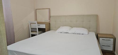 een slaapkamer met een wit bed en een spiegel bij Ajla Komuna Apartament in Tirana
