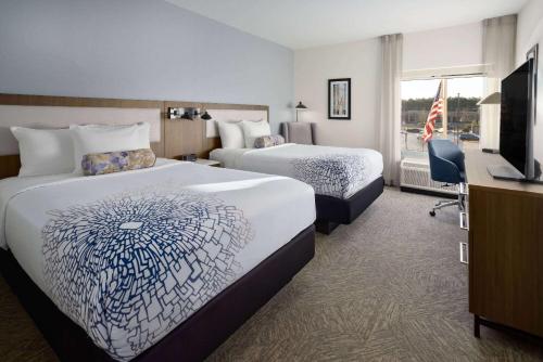 a hotel room with two beds and a television at La Quinta Inn & Suites by Wyndham Locust Grove in Locust Grove