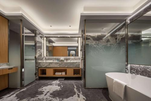 a bathroom with a tub and a large mirror at Wyndham Grand Zhaoqing Downtown in Zhaoqing
