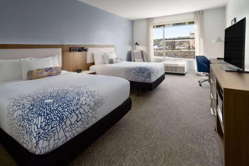 a hotel room with two beds and a flat screen tv at La Quinta Inn & Suites by Wyndham Locust Grove in Locust Grove