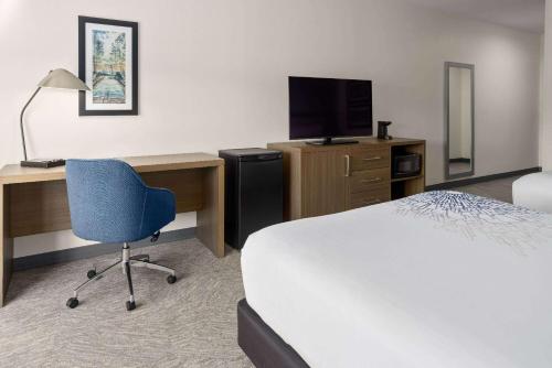a hotel room with a bed and a desk and a television at La Quinta Inn & Suites by Wyndham Locust Grove in Locust Grove